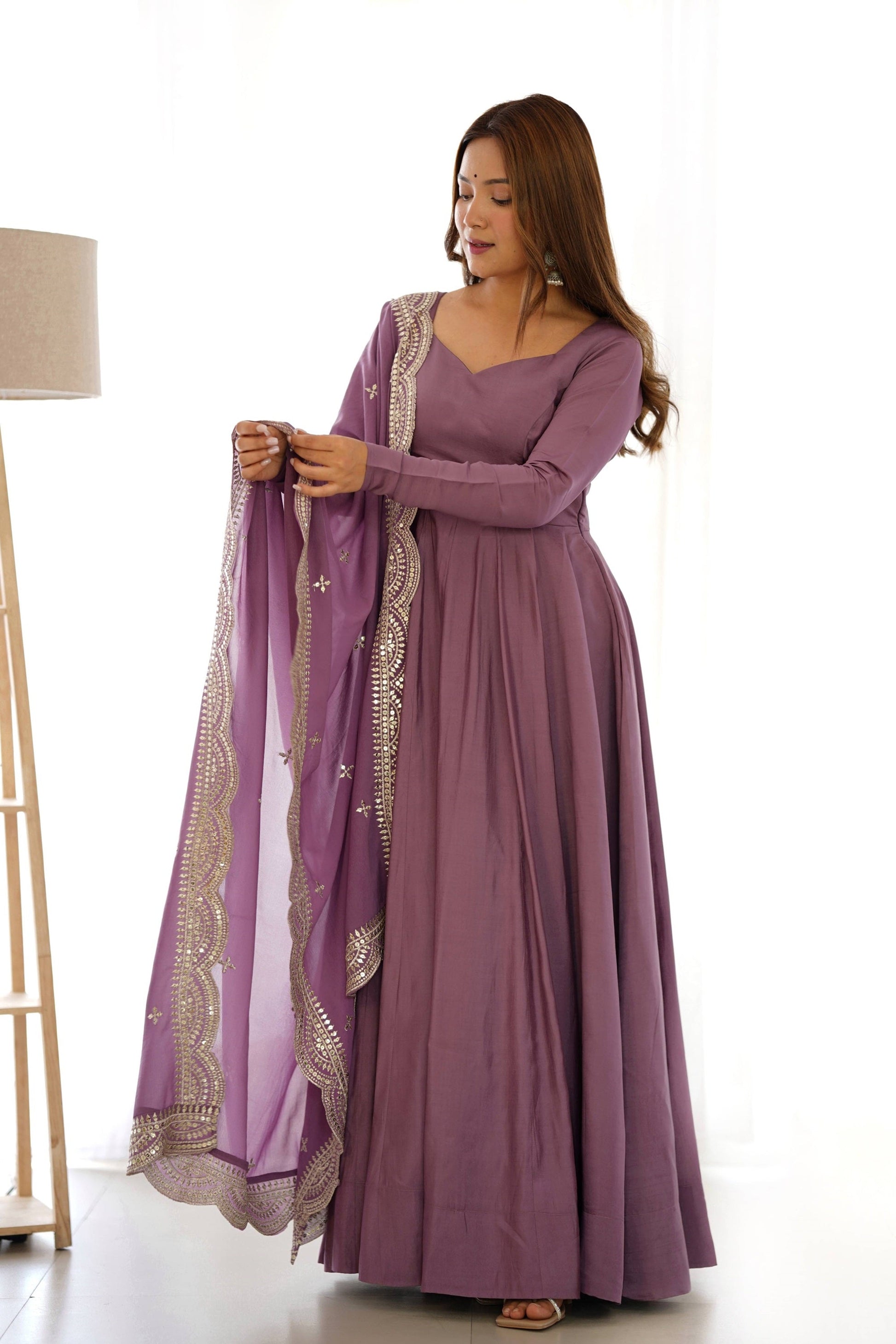 Woman wearing a long purple dress with a matching shawl on a white background