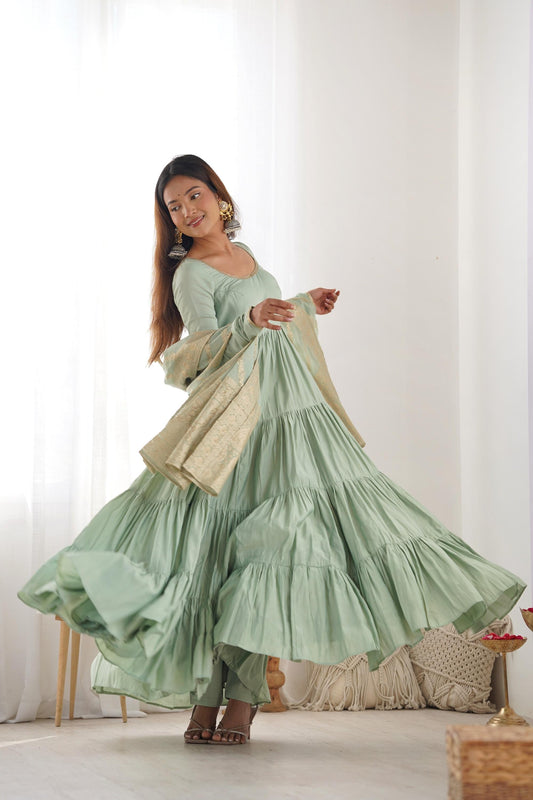 A woman wearing a flowing light green Anarkali suit with a heavy zari woven dupatta