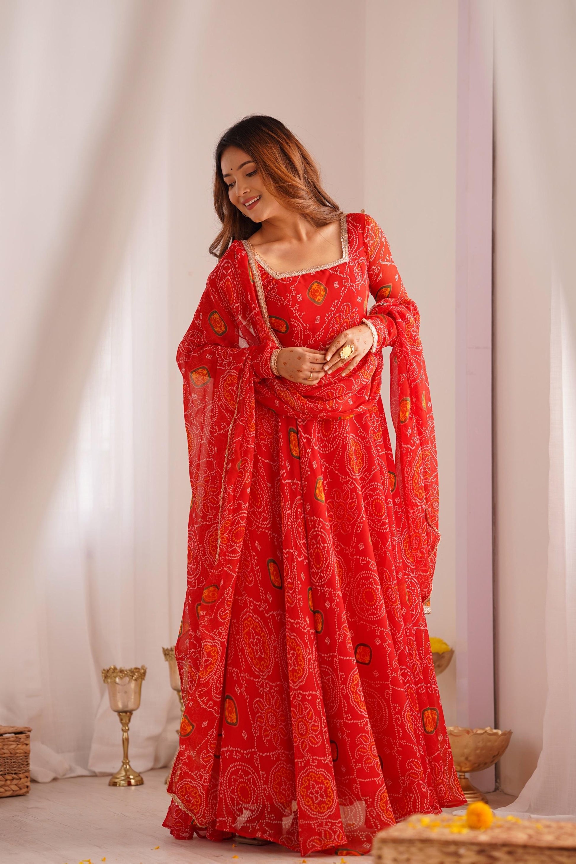 A woman wearing a flowing red Anarkali suit set with a dupatta and intricate bandhej print, showcasing the full front view